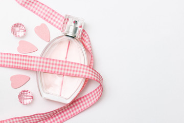 Bottle of parfume, pink hearts, crystals, plaid ribbon and place for a simple text on a light white background.