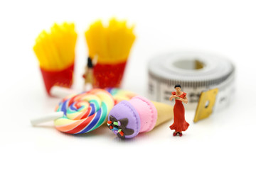 Fototapeta premium Miniature people : beautiful woman sitting on tape Measure with junkfood ,Healthcare and diet concept.