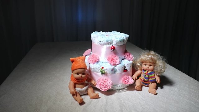 Slider shot. Cake of diapers, baby shower gift diaper, wrapped diapers, a roll of diapers, wrapped a clean diaper on table with baby doll decorated. Selective focus. Newborn greeting card  or gift
