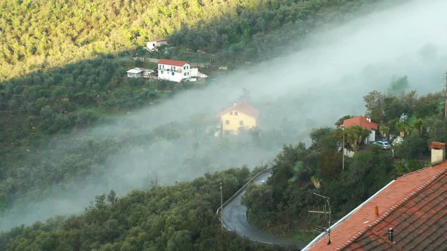 Early foggy morning in the Alpine town. Fog from the mountains makes its way along the medieval streets. Perinaldo, Liguria, Italy.