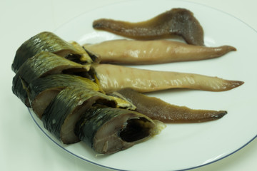 Smoked herring in white plate on old wooden table, top view .