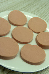 Sliced sausage with salad leaves over the wooden background .