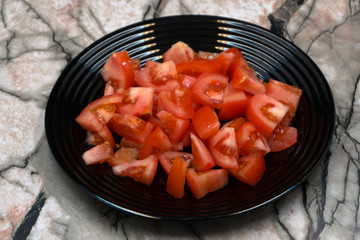 Vegetable salad - tomato, pepper, cucumber and greens on a white plate on a light background .