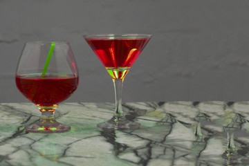 red martini cocktail splashing into glass on black background .