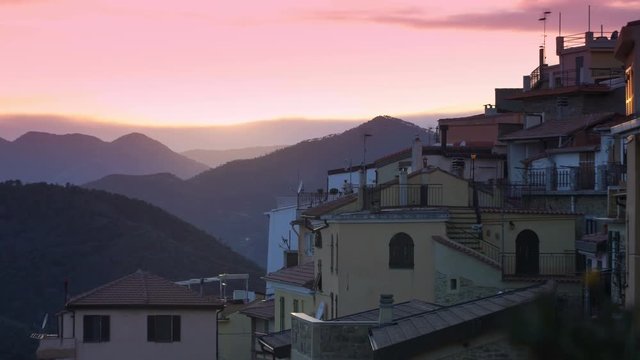The setting sun illuminates the roofs of a medieval town in the mountains. Perinaldo, Italy.