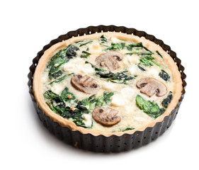 Traditional  french quiche pie with spinach and mushroom in metal baking form isolated on white