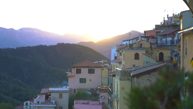 Early foggy morning in an alpine town. The rising sun illuminates the roofs of a medieval town in the mountains.. Perinaldo, Liguria, Italy.