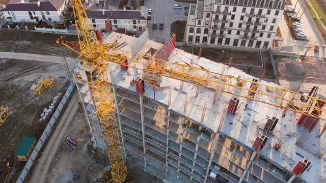 Construction site with a bird's eye on the Sunset. Video shooting with drone. New house near the road and shopping center. Flying over the construction site. The construction of the plant in the city.