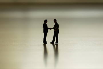 scenic of silhouette mini businessman shake hand for business deal