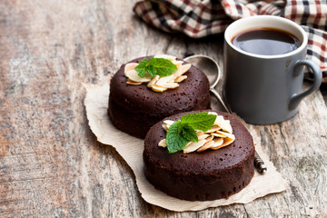 Chocolate  fondant with almonds and cup of coffee on wooden table
