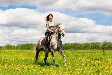 Woman riding on grey horse in the field
