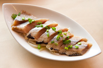 Sliced ??herring with green onion on a platter on the table