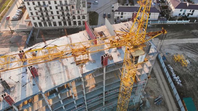 Construction site with a bird's eye on the Sunset. Video shooting with drone. New house near the road and shopping center. Flying over the construction site. The construction of the plant in the city.