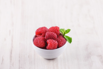 bowl with raspberries on a wooden background