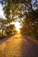 Obraz premium Old asphalt road on sunset with car