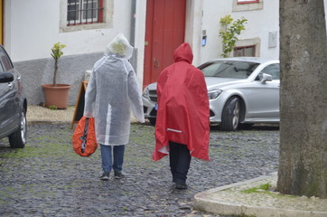 Menschen laufen mit Regenponcho durch Straße 
