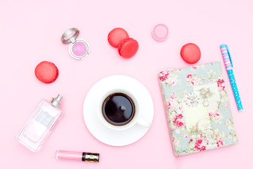 Female accessories and a cup of coffee on a pink background. Feminine desk