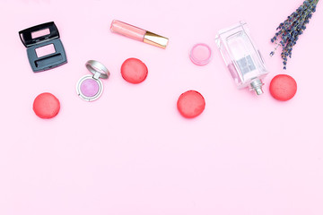 Set of cosmetics and strawberry macaroons on a pink background. Copy space