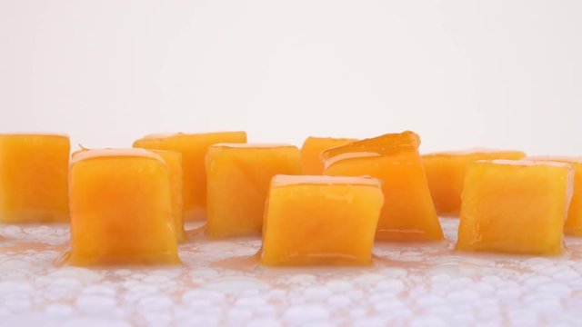 Juicy mango fruit slices rotating on turn table. Isolated on white background. Loopable. Close up macro. Angled view.