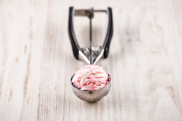 strawberry ice cream with utensil on wooden background