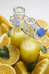 glass bottles with orange and straw on an orange background close-up.