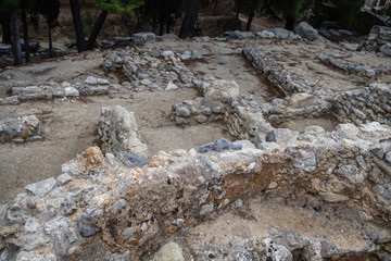 old, historic site, visible foundations of stone buildings and fragments of stone walls between trees