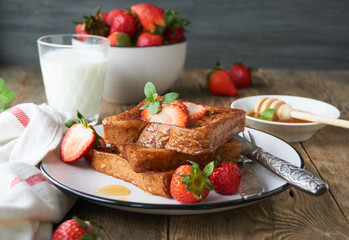 French toasts with honey and strawberries on a plate