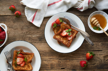 French toasts with honey and strawberries on a plate