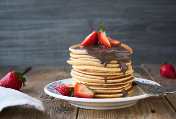 Stack of pancakes with strawberries and chocolate on a plate      