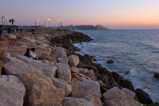 sunset at the rocky shore in Tel Aviv, in background Yaffa town