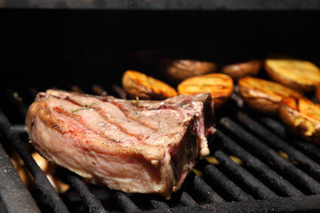 Preparation of steak on the grate and coals.
