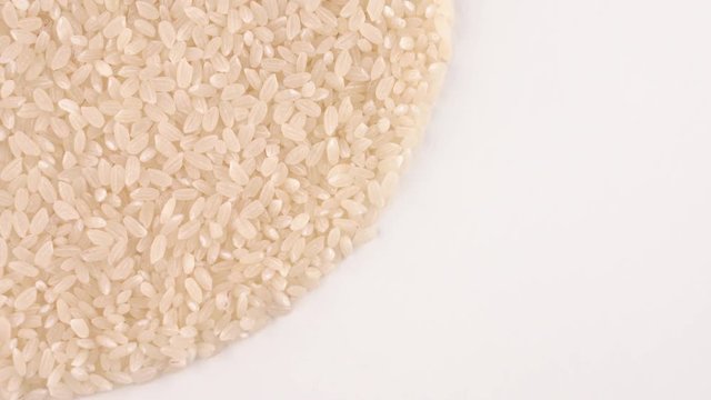 Half frame circle shaped heap of raw white rice rotating on turn table. Isolated on white. Loopable. Close up macro. View from above/overhead.