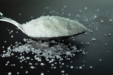 Sugar on spoon in black background