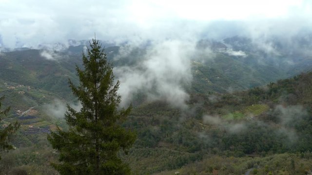 Early foggy morning in the Alps. Fog from the mountains falls into the valley. Perinaldo, Italy.