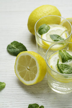 water with lemon, mint and lemons on a white wooden background.