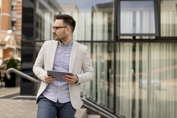 Young businessman with digital tablet by the office building