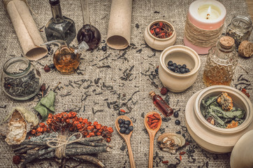 Herbal medicine concept. Alternative medicine. Dry wild rowan berry and apple berry, shelf fungus and other curative herbs essential oil and prescription scroll on burlap sackcloth background.