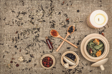 Fototapeta na wymiar Herbal medicine concept. Alternative medicine. Dry curative herbs and wild berry i jars and spoons and essential oil on burlap sackcloth background with copy space.