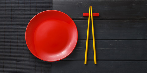 Empty plate and chopsticks on dark background