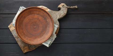 Empty clay plate on rustic cutting board