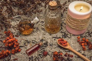 Herbal medicine concept. Alternative medicine. Dry curative wild rowan berry and apple tree berry herbs and essential oil on burlap sackcloth background.