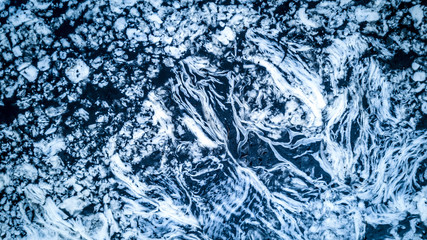 Aerial view of the ice frozen on the river. Blue and white pattern. Close up.