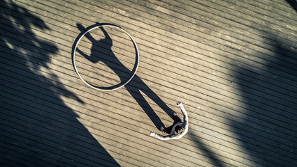Young man is standing on the square next to the cyr wheel. On shadow looks like he is holding this...