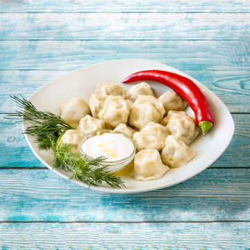 dumplings with sour cream and pepper on blue wooden background