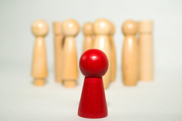 red isolated wooden figure in the foreground, blurred wooden figures in the background, systemic board, family therapy