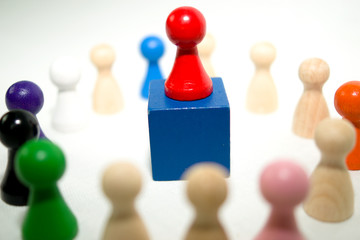 Obraz premium inner parts work with small red isolated wooden figure on blue cube, surrounded by many small wooden figures, systemic board, family therapy