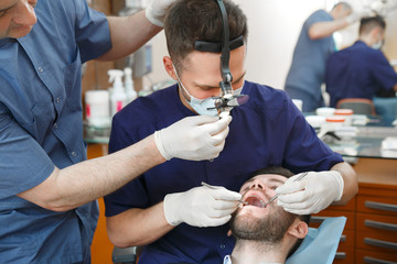 Obraz na płótnie Canvas A dentist with an assistant treats a patient's teeth.