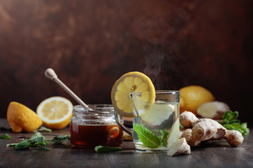 Ginger tea with honey , lemon and mint on old wooden table .