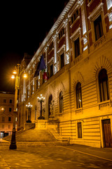 Fototapeta na wymiar Vertical View of the Back Side of the Italian Parliament Building, Montecitorio, at Night Illuminated by Warm Lights. Rome, Italy