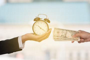 Unidentified business people hands show black alarm clock and dollar bank note, business concept...